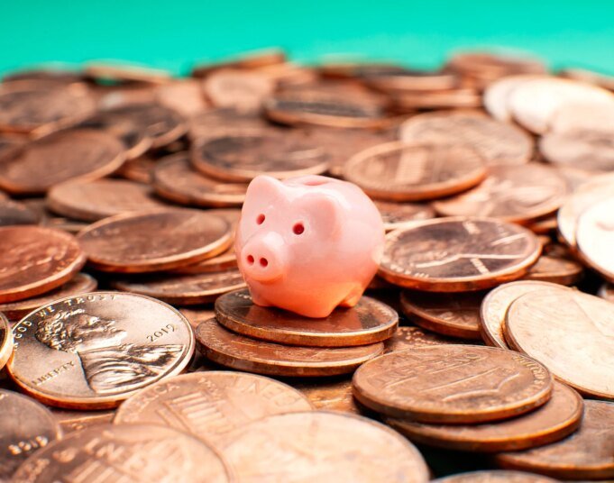 Savings concept - Tiny piggy bank on pennies