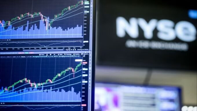 由於美國地區銀行的擔 Close-up of an E-Mini S&P 500 Futures chart on a monitor with NYSE signage blurred in the background.