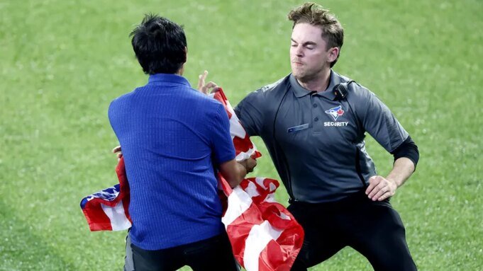 在世界職業棒球大賽第六場比賽中，一名揮舞著美國國旗的球迷衝進球場，引起了加拿大觀眾的尖叫聲。| mtgamer.com